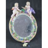 A late 19th century Continental floral encrusted oval easel mirror decorated with cherubs upon,