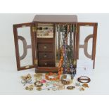 A two-door jewellery cabinet containing quantity of assorted costumer jewellery inc brooches, rings,