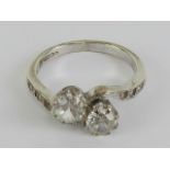 A 9ct white gold crossover ring having twin round cut white stones with further smaller white