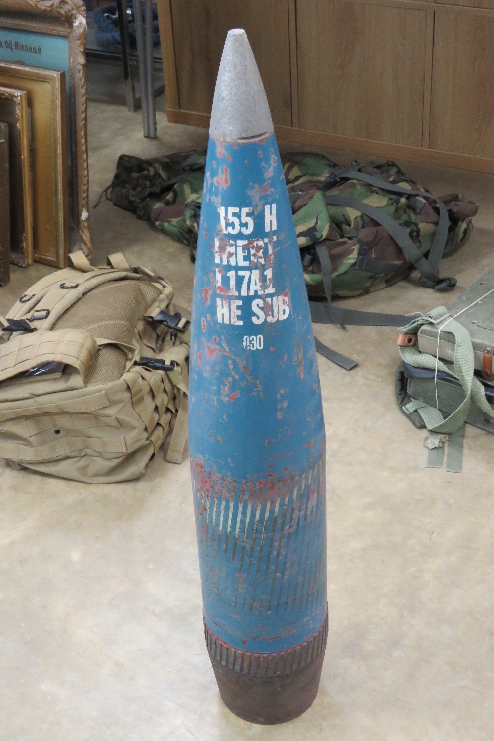 An inert 155mm HE shell head standing 88