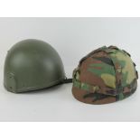 Two helmets one having camouflage fabric cover.