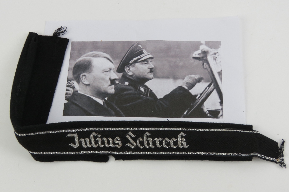 A WWII German SS Officers cuff title 'Julius Schreck' having tunic remnants attached.