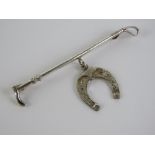 A silver stock pin or brooch in the form of a riding crop with horse shoe under, marked sil,