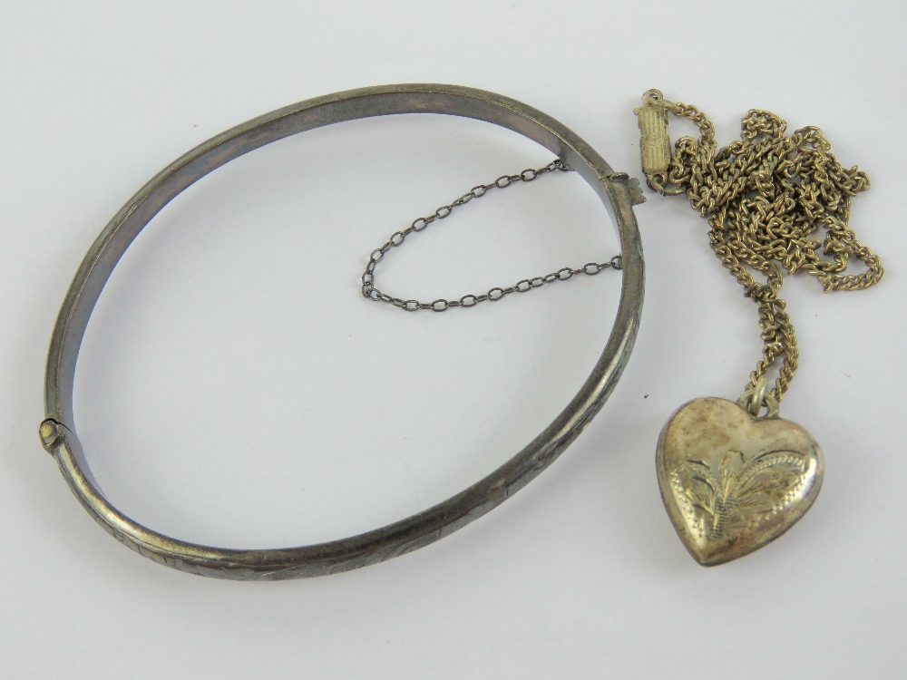 A silver heart shaped pendant on fine white metal chain,