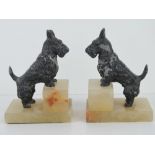 A pair of Scotty dog bookends, each raised over square shaped white onyx stepped base, 16cm high.