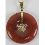 A 14ct gold red jade disc pendant having Chinese character to centre, 2.3cm dia, stamped 14k.