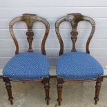 A pair of Victorian mahogany machine carved dining chairs raised over circular turned legs.
