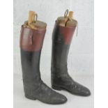 A pair of black and brown leather riding boots, having interior finger pulls,