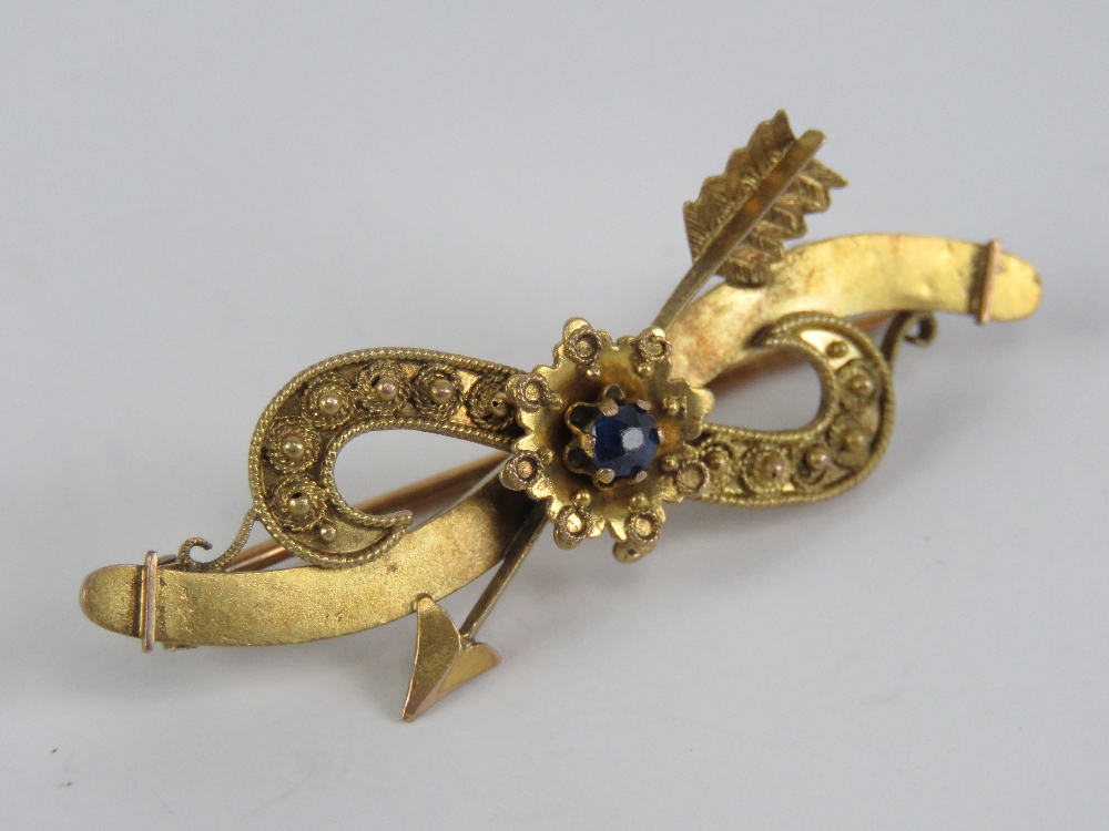 A gold and sapphire brooch having arrow and flower design, indistinct marks to back, 4.2cm wide. 2.