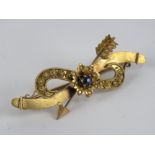 A gold and sapphire brooch having arrow and flower design, indistinct marks to back, 4.2cm wide. 2.