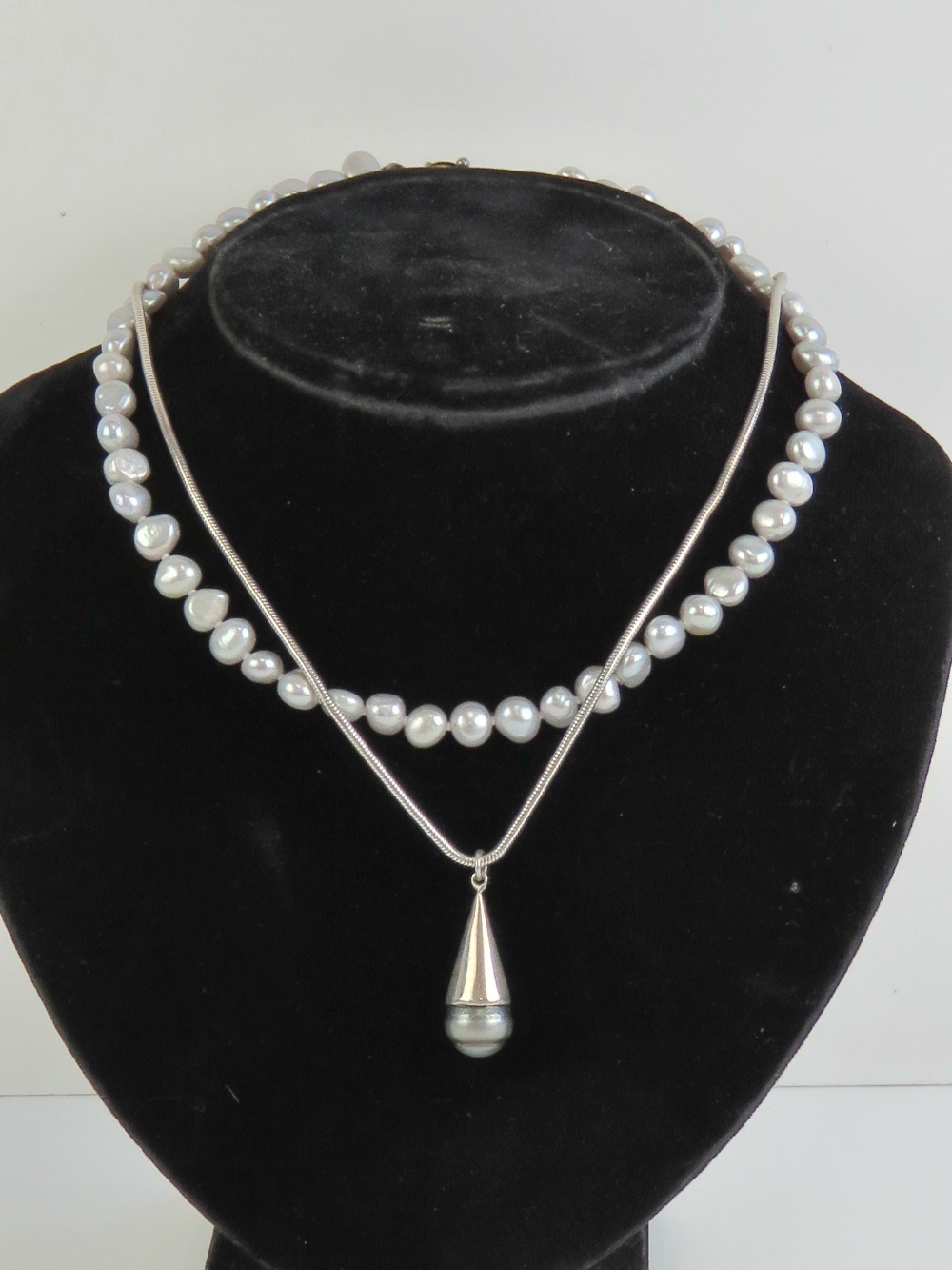 A grey pearl pendant on 925 silver chain together with a grey pearl necklace having 925 silver