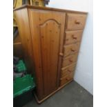 A pine cupboard having single door and six short drawers.