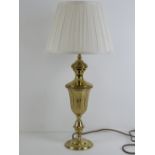 A brass table lamp base of urn form having silk lamp shade, all measuring 60cm high.