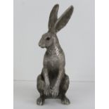 A silver coloured figurine of a Hare sat on its hind legs, 18cm high.