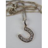 A silver horseshoe pendant set with white stones with fine silver chain.