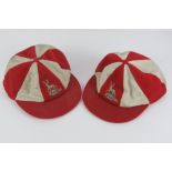 A pair of Harrods red and white peaked team chase caps, each bearing a Stag upon.