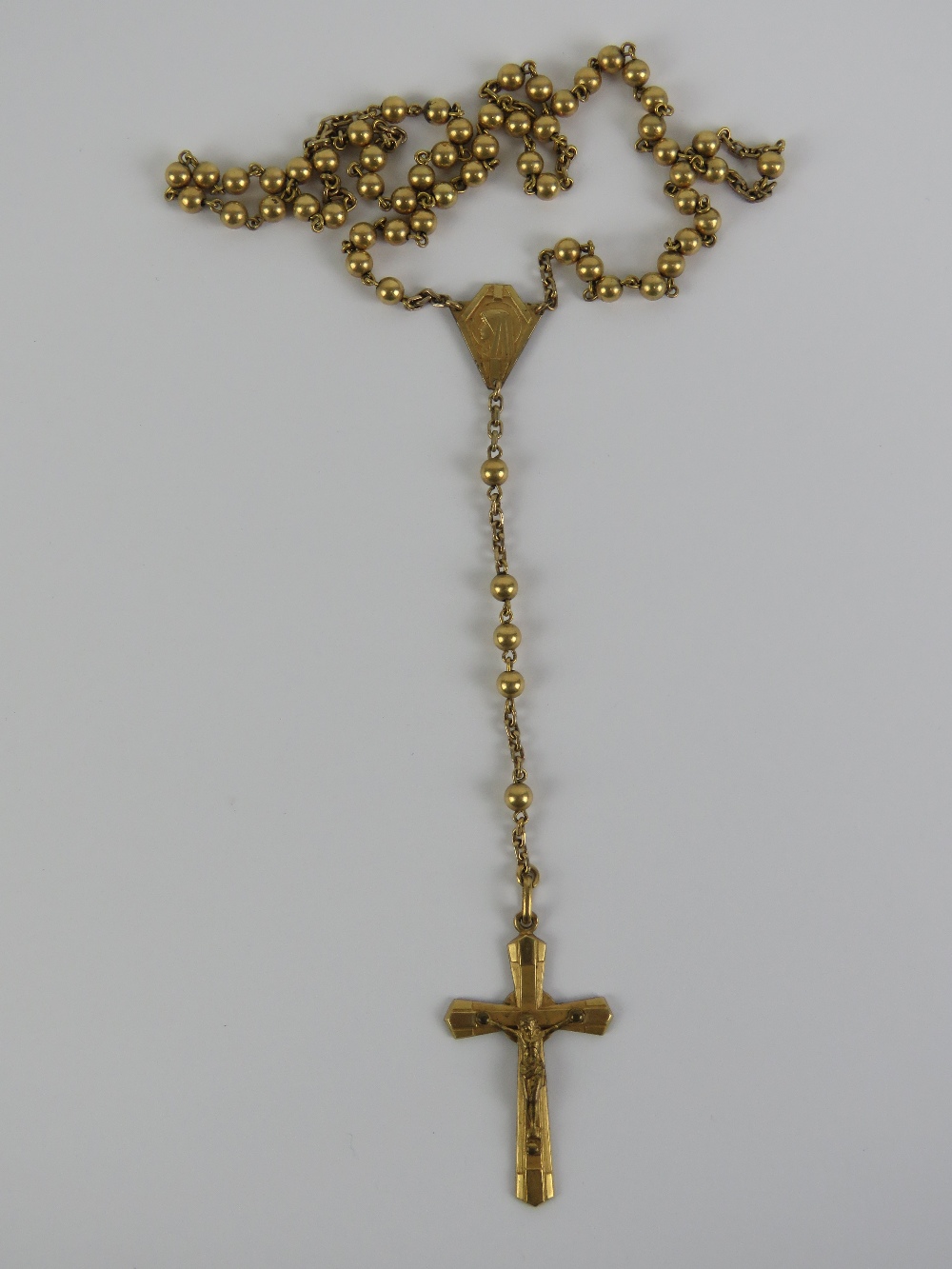 A gilt metal rosary having crucifix upon