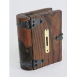 A wooden money box in the form of a book, having brass escutcheon and black metal hinges. 18 x 15cm.
