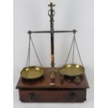 An impressive set of brass balance scales set on mahogany base with drawer under,