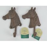 A pair of cast iron coat hooks in the form of horses heads, 19cm high.
