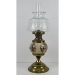 A brass oil lamp having ceramic reservoir with continental figural garden scenes upon,
