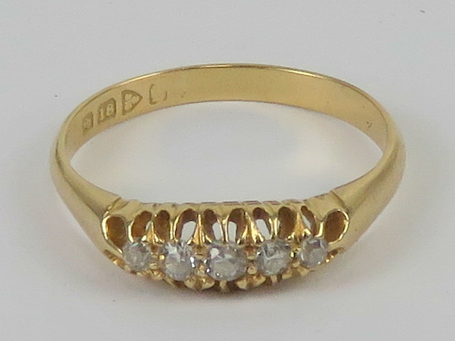 An 18ct gold diamond ring having carved head set with five graduated round cut stones,