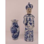 A blue and white Oriental ceramic figurine of a gentleman in hat and robes having dragon design