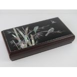 An Oriental lacquered box inlaid with mother of pearl scene of birds flying and perched on bamboo,