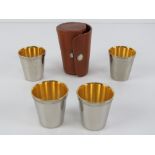 A pigskin leather studded tot cup holder containing four gilded tot cups within,