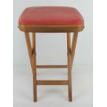 A vintage 1960's beech folding stool with red leatherette seat, 50cm high.