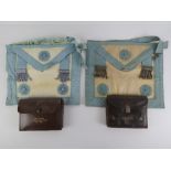 Masonic; Two leather regalia pouches each containing a lambskin apron, marked respectively for Bro.