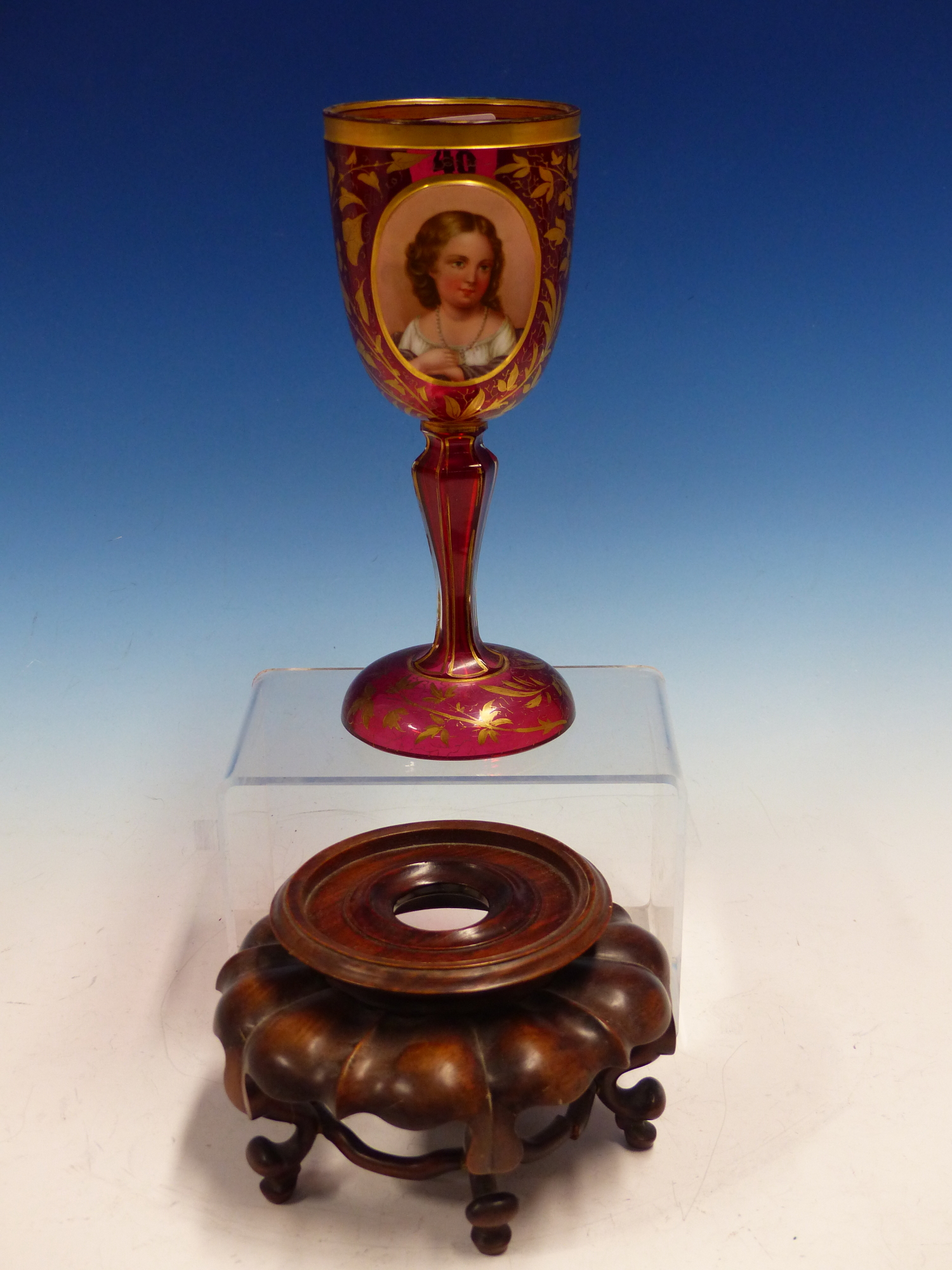 A BOHEMIAN GILT RUBY GLASS GOBLET ON A CHINESE WOOD STAND.