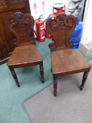 A PAIR OF CARVED OAK EARLY VICTORIAN SHIELD BACK HALL CHAIRS.