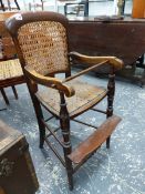 A STAINED WOOD CHILD'S CANED BACK HIGH CHAIR, THE PIERCED SEAT ABOVE A FOOT REST JOINING THE