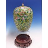 A CHINESE YELLOW GROUND JAR AND COVER PAINTED WITH BOYS AMONGST SCROLLING FOLIAGE ON A WOOD STAND