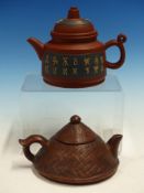 TWO YIXING TEA POTS AND COVERS, ONE WITH BEIGE SCRIPT ON BLUE PANELS AND THE OTHER BASKET MOULDED