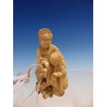 A JAPANESE IVORY OKIMONO OF TWO CHILDREN FEEDING A PUPPY. H.8cms.