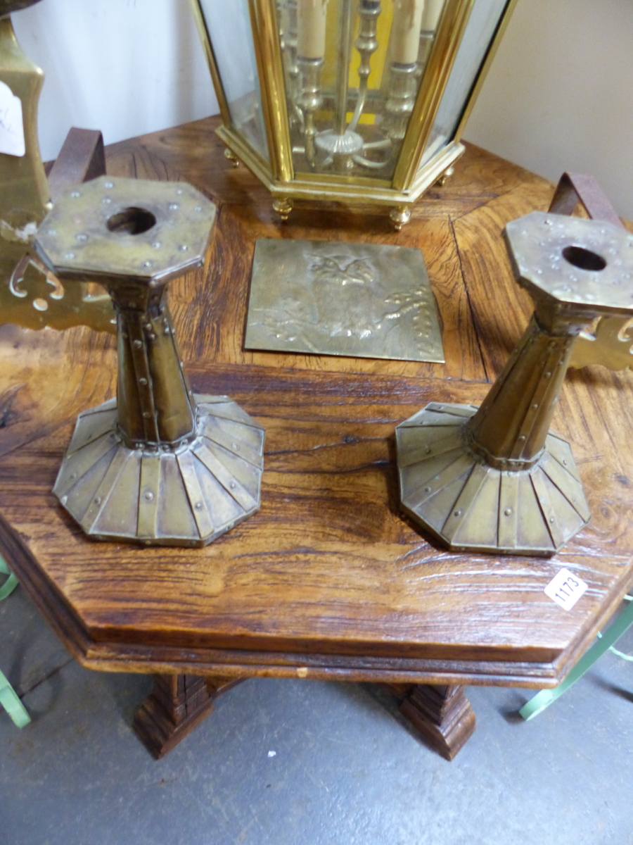 A PAIR OF ARTS AND CRAFTS CANDLESTICKS AND AN EMBOSSED BRASS PANEL.