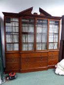 A GEORGIAN MAHOGANY BREAKFRONT BOOKCASE WITH FOUR GLAZED DOORS OVER A NINE DRAWER BASE, CARVED BREAK