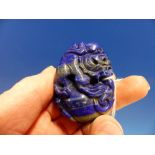 A CHINESE BANDED LAPIS LAZULI MATRIX PENDANT PIERCED AND CARVED AS A BUDDHIST LION ON TOP OF A