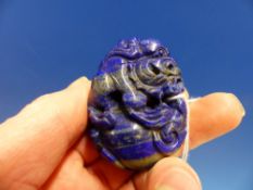 A CHINESE BANDED LAPIS LAZULI MATRIX PENDANT PIERCED AND CARVED AS A BUDDHIST LION ON TOP OF A