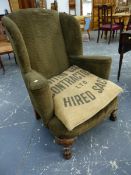 A WING ARMCHAIR UPHOLSTERED IN DARK OLIVE CORDUROY, THE STAINED WOOD FRONT LEGS CARVED WITH SHELLS