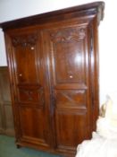 A FRENCH PROVINCIAL CARVED OAK ARMOIRE WITH TWO FULL HEIGHT PANEL DOORS ENCLOSING HANGING AND