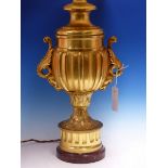 A GILT BRONZE LAMP BASE OF FLUTED BALUSTER SHAPE WITH FOLIATE HANDLES THE CIRCULAR FOOT ON RED