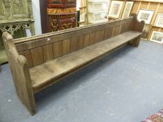 A LARGE ANTIQUE OAK PEW WITH PANEL BACK AND SHAPED ENDS. W.334 x D.50 x H.94cms.