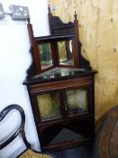 A FLOOR STANDING CORNER CABINET MIRRORED UNDER THE RECESSED EBONISED SHELF TOP, THE GLAZED DOORS