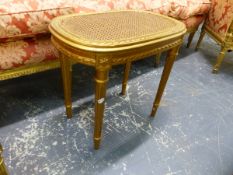 A CARVED GILTWOOD DRESSING STOOL WITH CANE SEAT.