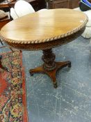 A COLONIAL HARD WOOD CIRCULAR TABLE WITH GADROONED RIM AND FOLIATE RELIEF CARVED APRON, THE CARVED