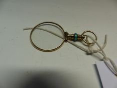 A YELLOW METAL AND TURQUOISE MOUNTED EYE GLASS.