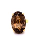 AN 18ct YELLOW GOLD AND SMOKY QUARTZ LARGE OVAL CUT RING. THE CENTRAL QUARTZ MOUNTED IN A FOUR